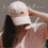 Animierte Bildfolge der beigen Cap mit roter Herz- und „Oh Happy Day“-Stickerei in sommerlichen Lifestyle-Szenen