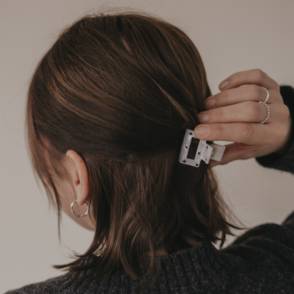 Hand befestigt kleine eckige Haarspange mit schwarzen Herzen im Haar