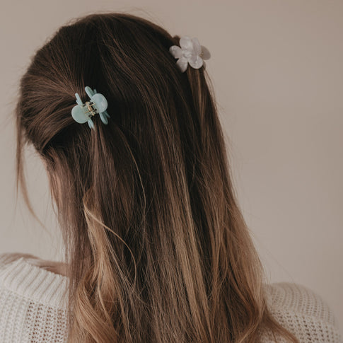 Haarspange Blume in Perlmutt-Optik in der Hand präsentiert