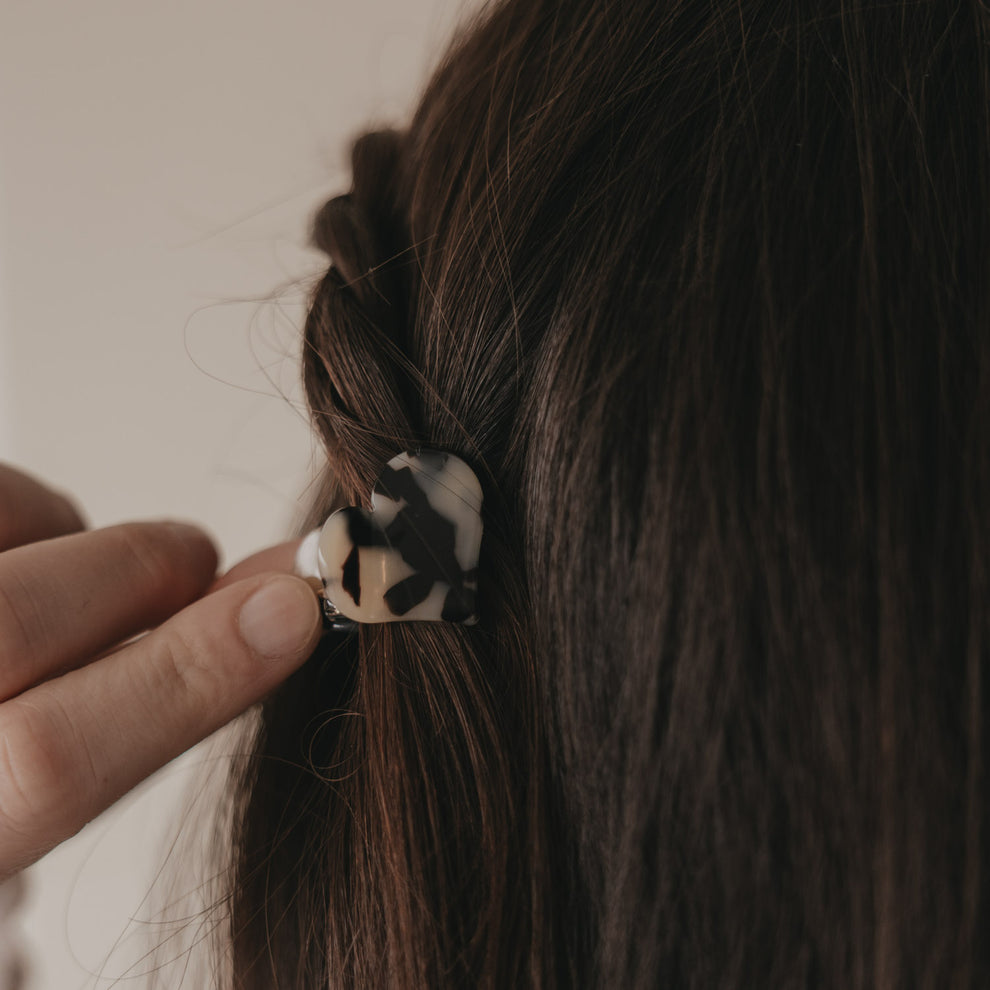 Kleine Haarspange in Herzform mit Leo-Muster wird ins braune Haar eingesetzt