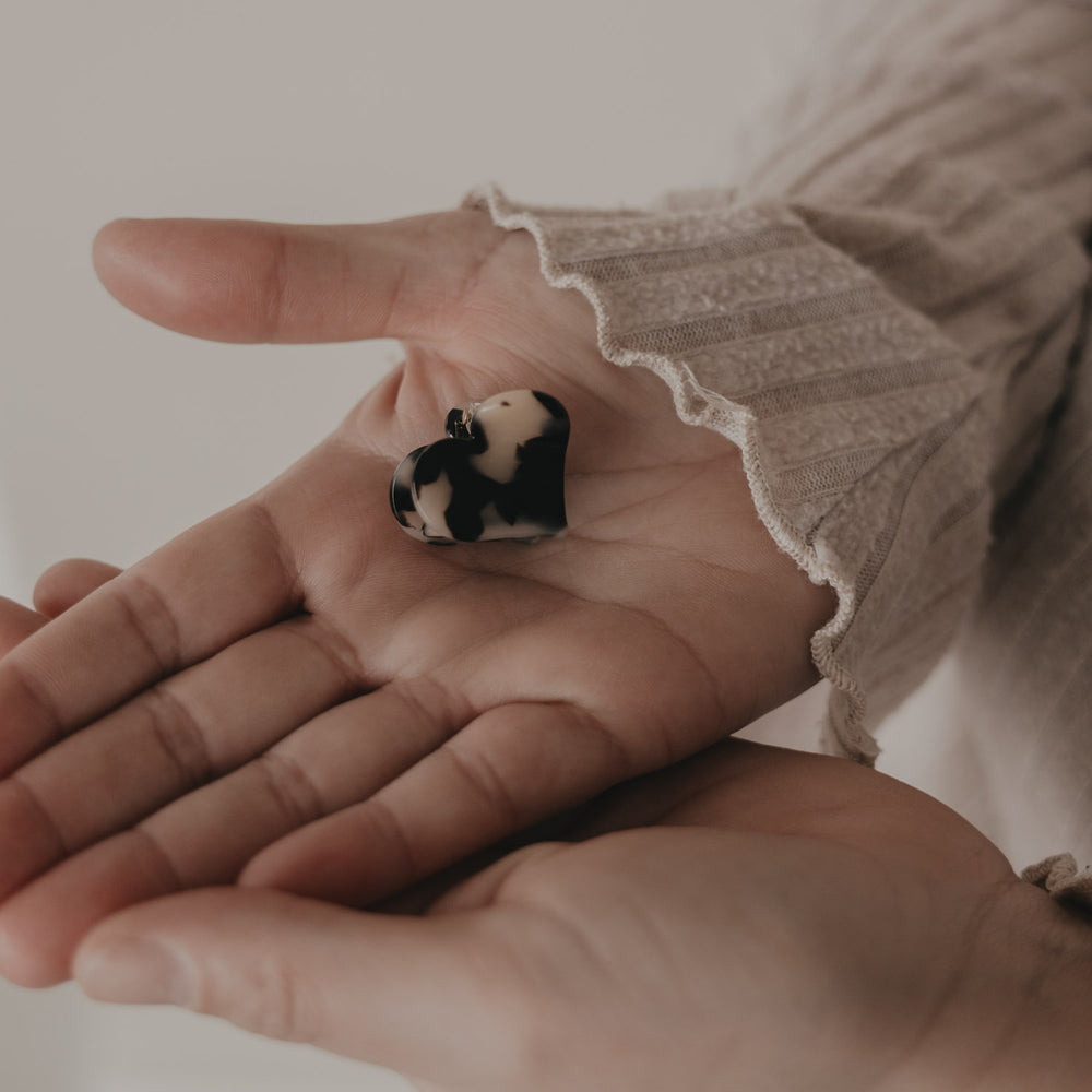 Kleine Haarspange in Herzform mit Leo-Muster auf der Hand präsentiert