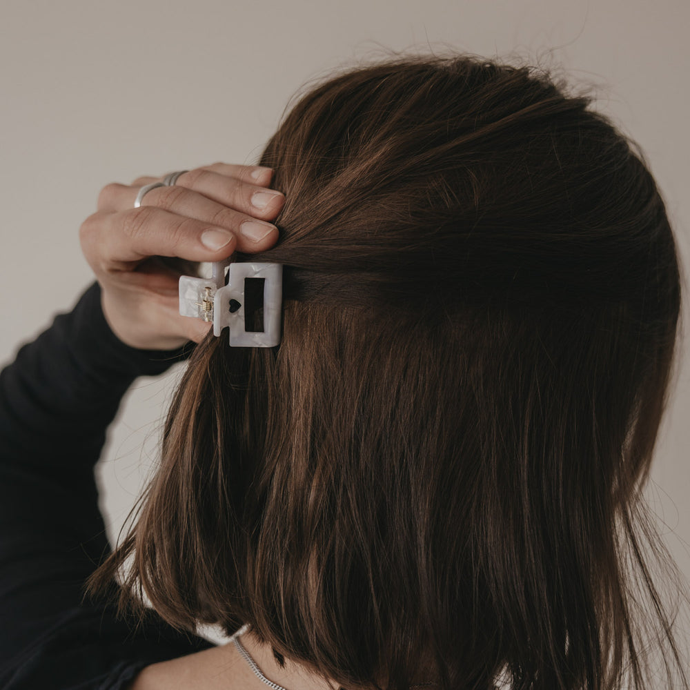 Hand befestigt kleine eckige Haarspange mit schwarzem Herz im Haar