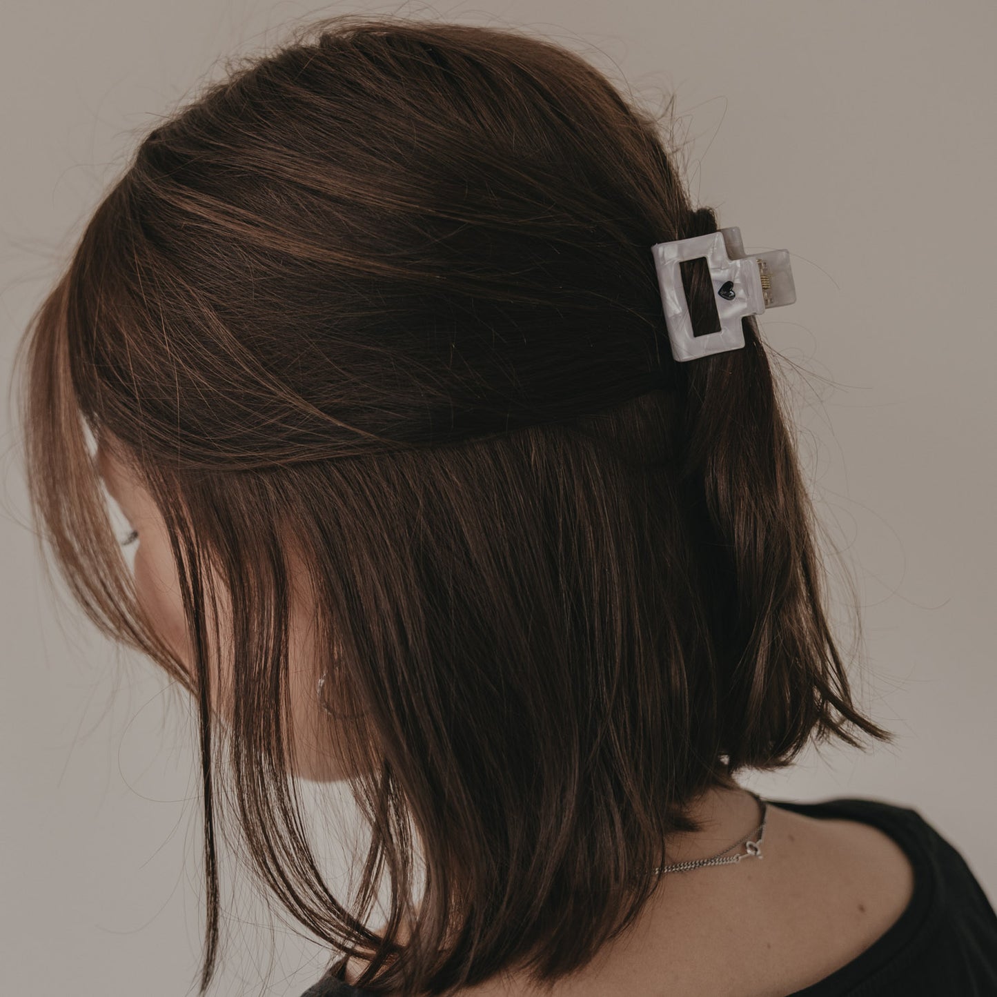 Kleine Haarspange eckig in Perlmutt-Optik mit schwarzem Herz im Haar getragen