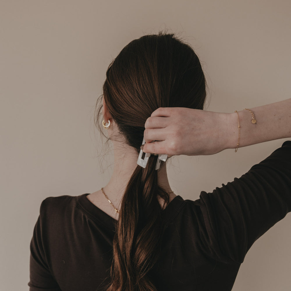 Hand befestigt große eckige Haarspange mit schwarzem Herz im Zopf