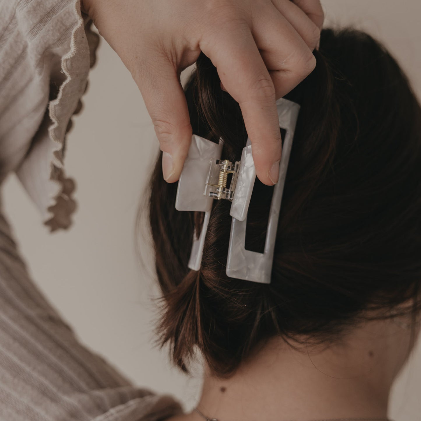 Hand öffnet maxi eckige Haarspange mit schwarzem Herz im Haar