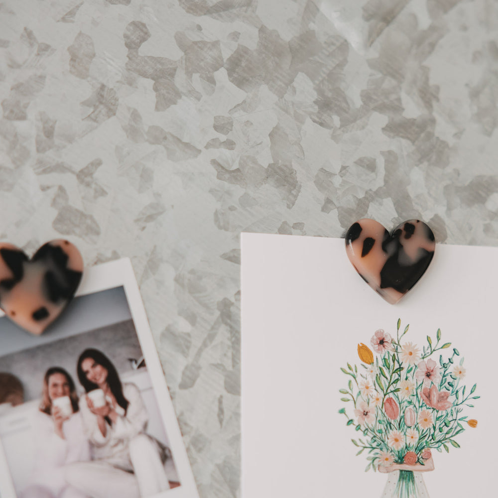 Herzmagnet im Leo-Look befestigt eine illustrierte Blumenkarte an einer magnetischen Pinnwand