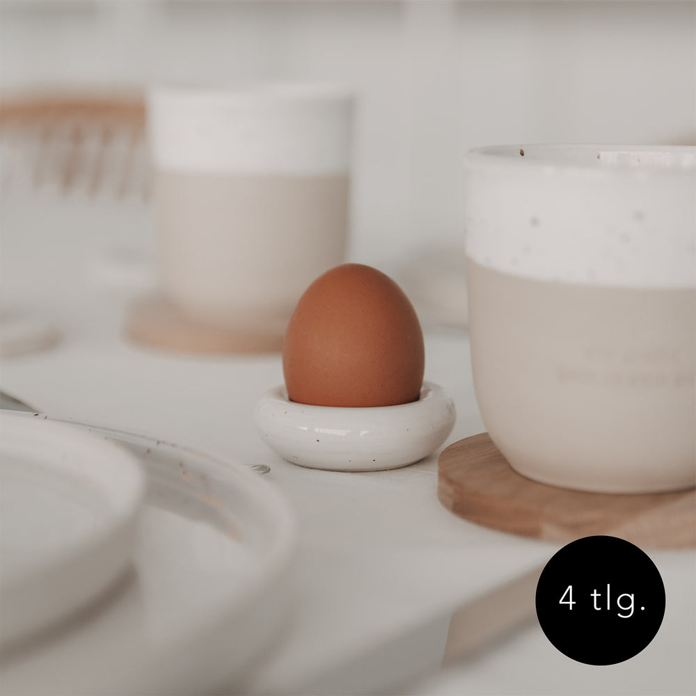 Minimalistischer Eulenschnitt Eierbecher Calma mit braunem Ei auf gedecktem Tisch, 4-teiliges Set.