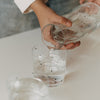 Wasser wird aus einer Glaskaraffe mit kleinen schwarzen Herzen in ein passendes Trinkglas gegossen