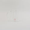 Karaffe aus Glas mit rosa Herzfigur im Inneren, minimalistisch vor weißem Hintergrund inszeniert.