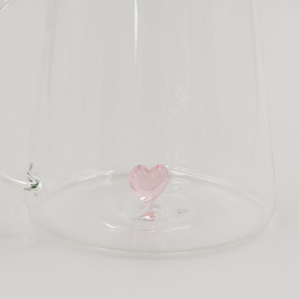 Detailansicht der filigranen rosa Herzfigur am Boden der Glaskaraffe.