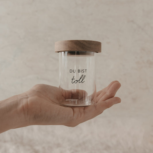 Kleines Vorratsglas mit Holzdeckel und Schriftzug „Du bist toll“ in einer Hand