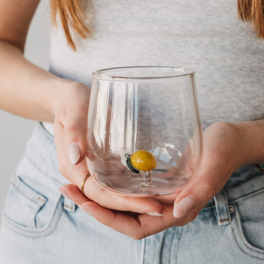 Glas mit Zitronen Motiv in Händen gehalten, stilvolles Trinkglas für Wasser und Getränke