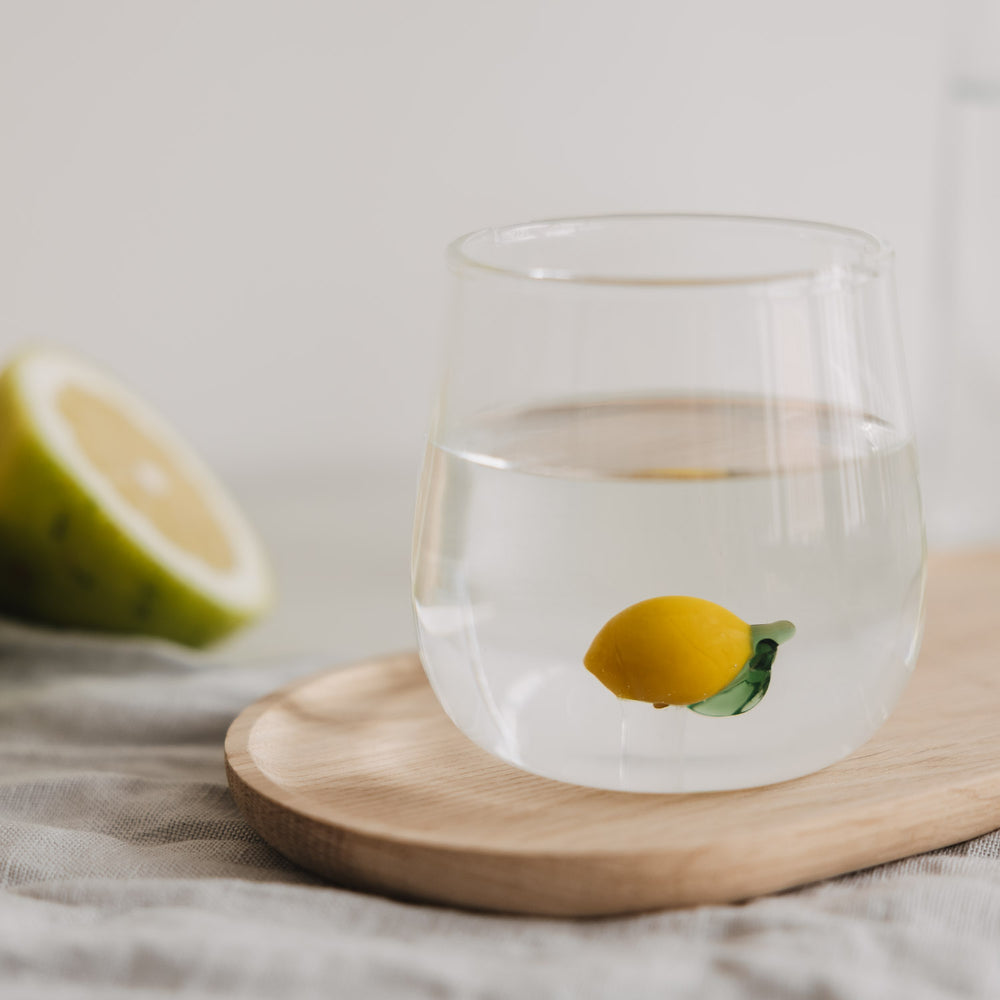 Glas mit Zitronen Motiv gefüllt mit Wasser, stilvoll auf Holzbrett inszeniert