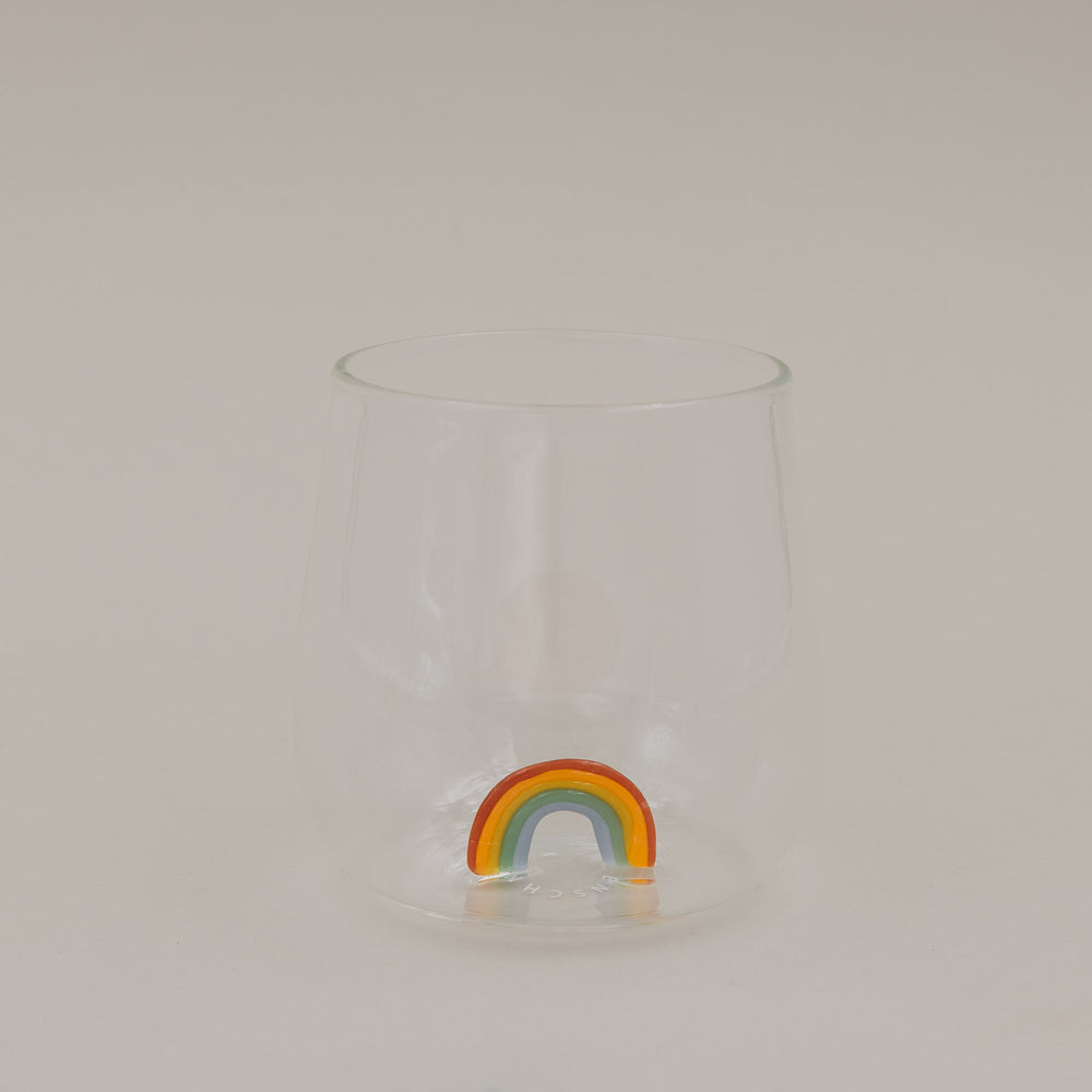 Klares Trinkglas mit buntem Regenbogen am Boden, schlichtes Design freigestellt