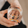 Draufsicht Glas mit Wasser und Regenbogen Design, modernes Trinkglas in Händen gehalten