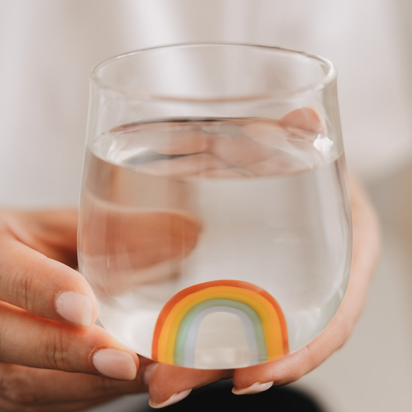 Detail Glas mit Regenbogen Motiv in Händen, minimalistisches Trinkglas für Getränke
