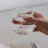 Glas mit Schwein-Motiv, gefüllt mit Wasser, auf gedecktem Tisch mit Besteck