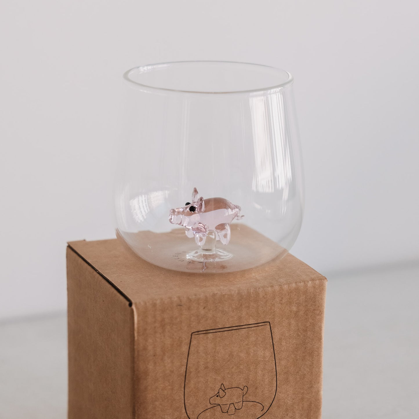 Trinkglas mit integrierter Schwein-Figur auf Verpackung, dekoratives Glas als Geschenkidee
