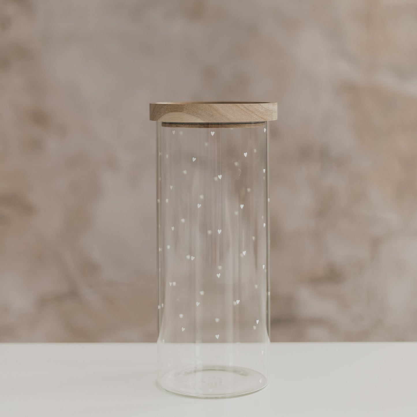 Leeres hohes Vorratsglas mit kleinen weißen Herzen und rundem Holzdeckel