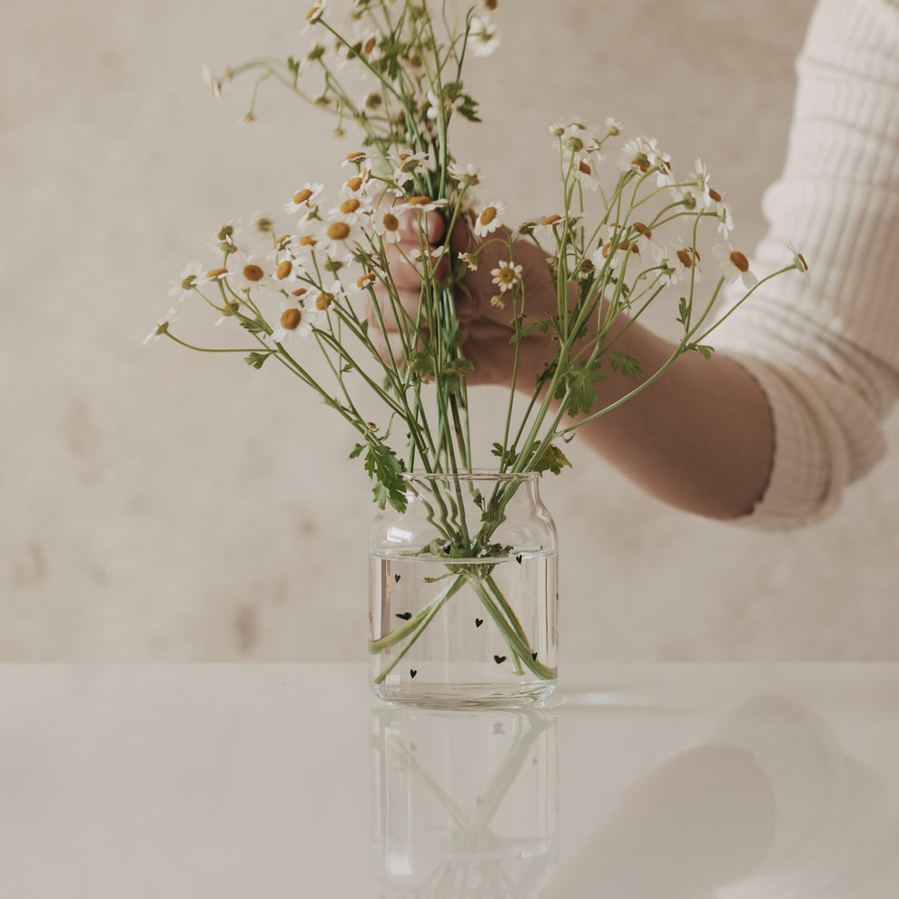 Glasvase mit schwarzen Herzen, mit locker arrangierten Blumen