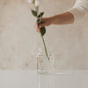 Glasvase mit schwarzen Herzen beim Arrangieren von Blumen
