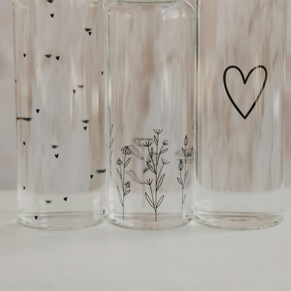 Glas Trinkflaschen mit Herz und Blumenwiese Design in Nahaufnahme, minimalistisch