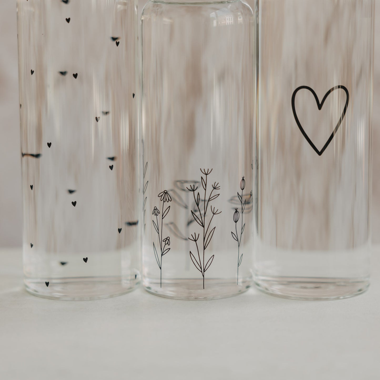 Detail Glasflaschen mit feinen Herz- und Blumenillustrationen im transparenten Design