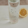 Glasflasche mit kleinen schwarzen Herzen und Zitronenscheibe, frisches Getränk