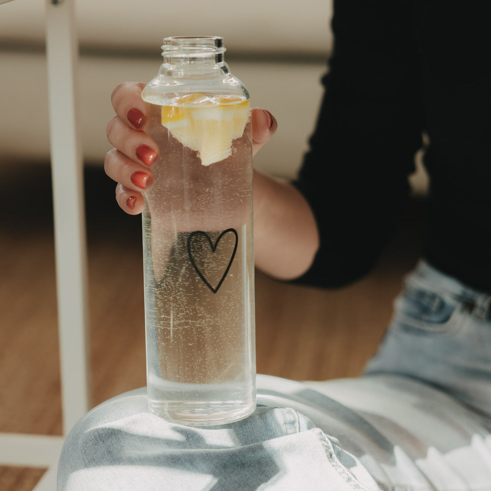 Glas Trinkflasche Herz 750 ml in der Hand, gefüllt mit sprudelndem Zitronenwasser