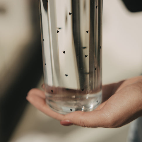 Detail Glas Trinkflasche mit kleinen Herzen, Bodenbereich in der Hand gehalten, Lichtreflexe sichtbar