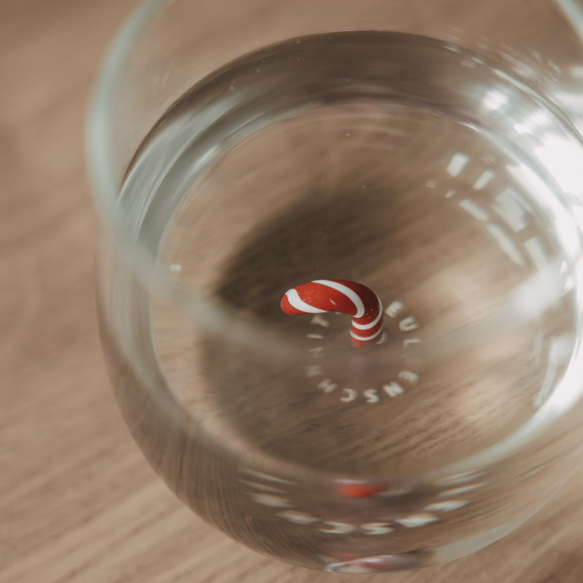 Detailaufnahme des Glasbodens mit rot-weißer Zuckerstange und Eulenschnitt Schriftzug.