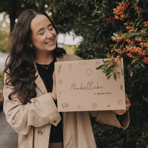 Herbstbox mit Zweigen und Beeren, liebevoll gehalten von Frau, ideales Geschenk für herbstliche Stimmung und Deko.