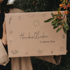 Nahaufnahme der Herbstbox mit Illustrationen und dem Text „Herbstliebe in deiner Box“ vor Beerenzweigen.