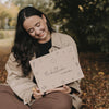 Frau sitzt im Laub und hält die Herbstbox mit herbstlichen Motiven, ideales Geschenk für die gemütliche Jahreszeit.