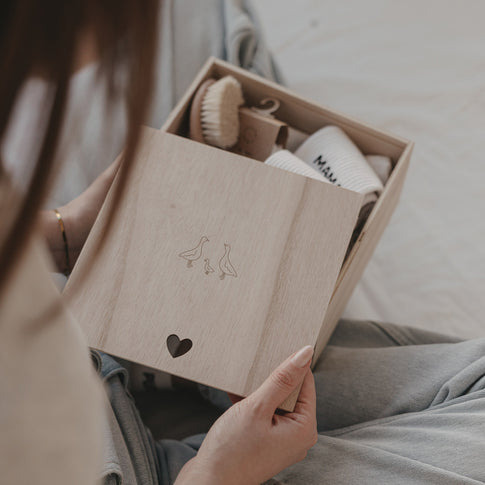 Holz Erinnerungsbox mit Gänsemotiv und Herzdetail, gefüllt mit Babygeschenk, stilvolle Aufbewahrung für Erinnerungen
