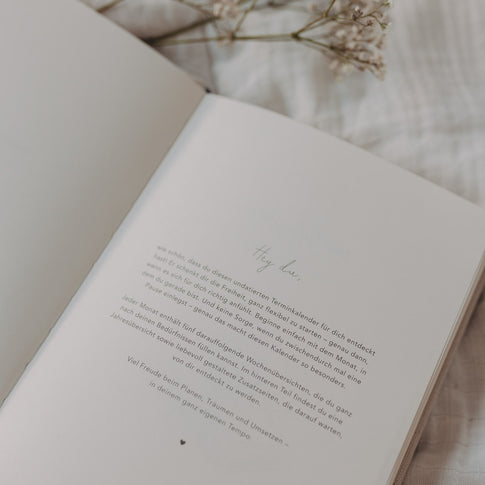 Einleitungsseite des Kalenders Neues Glück mit Begrüßungstext und zarter Typografie.