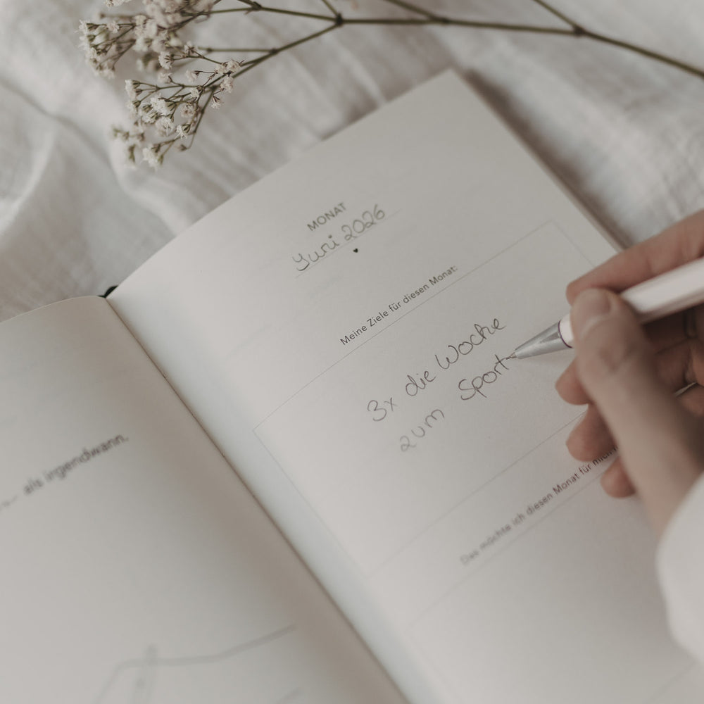 Monatsziel-Seite im Kalender „Neues Glück“ mit handschriftlichem Eintrag und Fokus auf persönliche Ziele