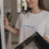 Frau öffnet Ofentür, trägt weißes Shirt mit blauem „breakfast club“-Schriftzug.