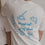 Rückansicht mit Frühstücksillustrationen und „breakfast club“-Aufdruck auf weißem Shirt.