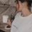 Frau mit weißem Shirt und blauem „breakfast club“-Aufdruck trinkt Kaffee.