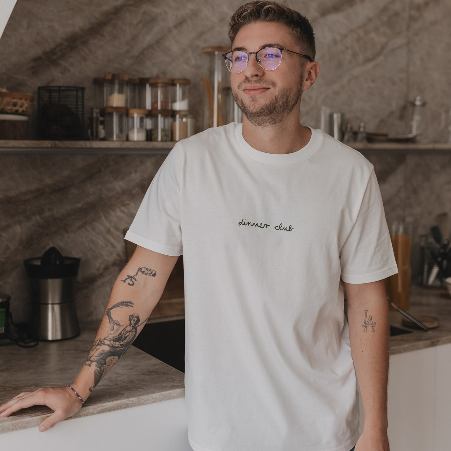 Locker sitzendes Dinner Club Shirt in Weiß, schlichtes Frontdesign in grüner Schrift.