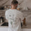 Rückansicht eines Mannes mit weißem Dinner Club Shirt und grünen Food-Icons in moderner Küche.