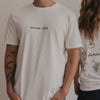 Fokus auf Frontdruck „dinner club“ in Grün, getragen von Person im weißen Shirt.