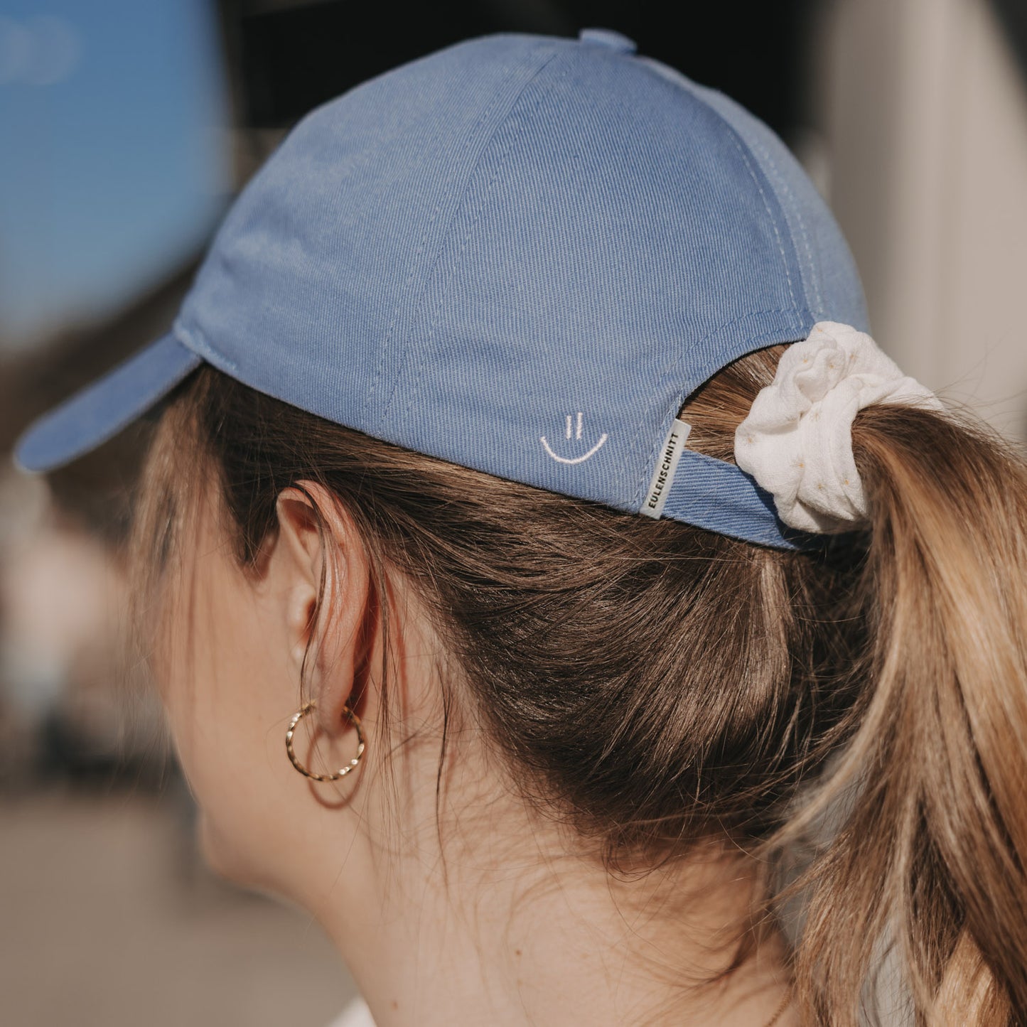 Rückansicht hellblaue Cap mit Smiley-Stickerei und Pferdeschwanz