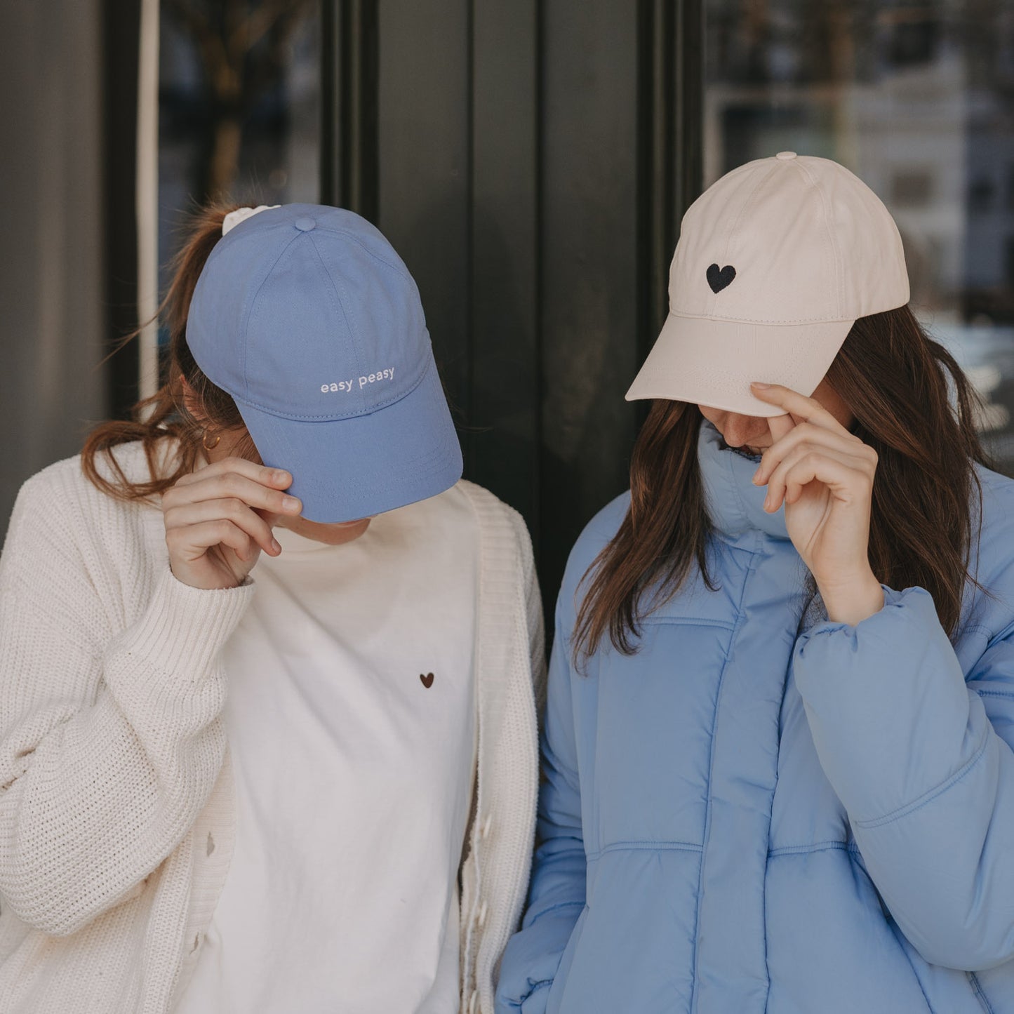 Zwei Frauen mit Caps: blaue „easy peasy“ Cap und beige Cap mit Herz-Stick