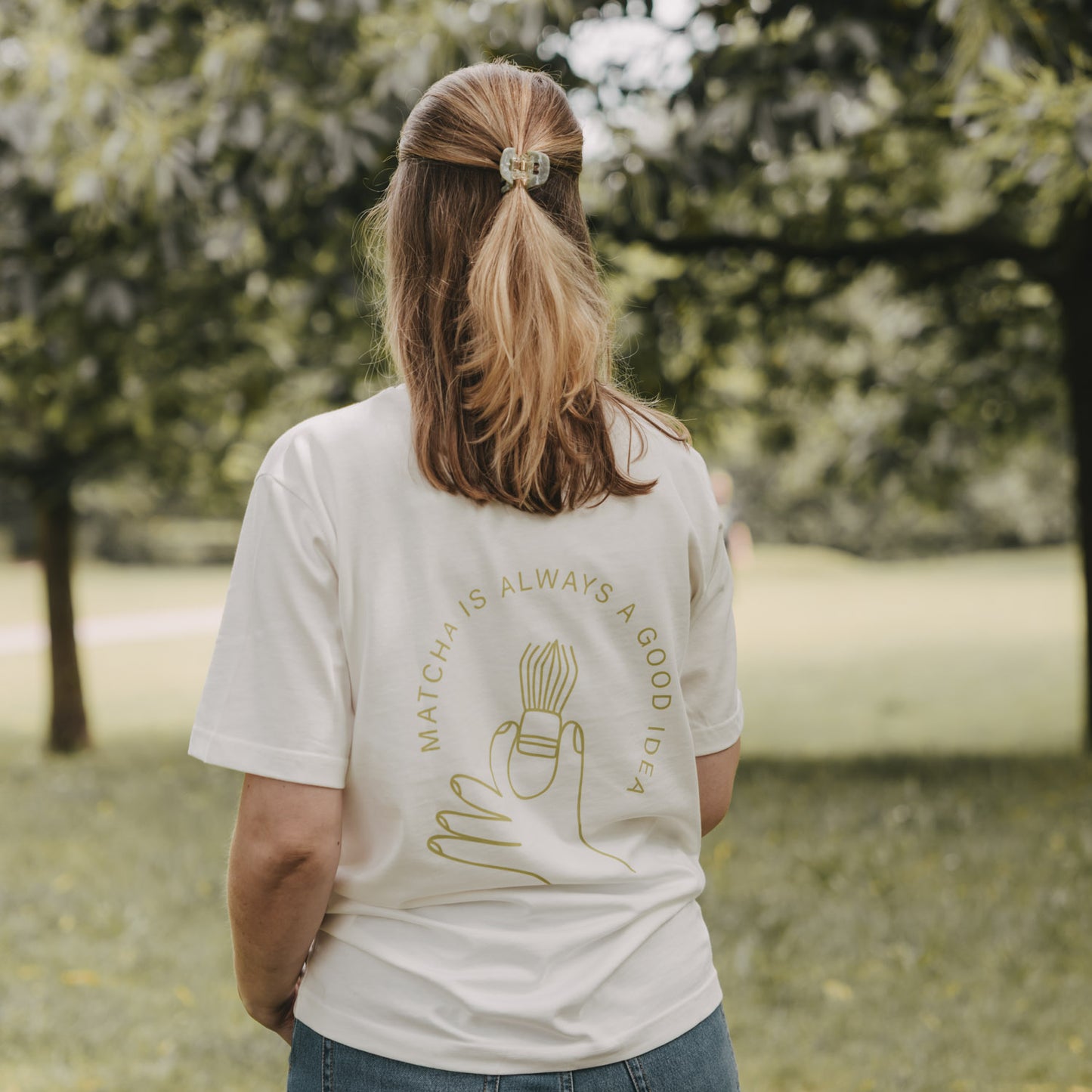 Frau von hinten mit weißem T-Shirt „Matcha is always a good idea“, Outdoor im Park