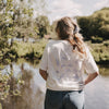 Frau von hinten am Wasser, weißes T-Shirt mit großem „go with the flow“ Print und Illustrationen