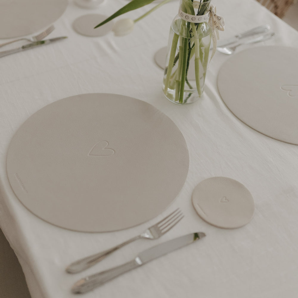 Warmes Tischarrangement mit cremefarbenem Platzset und Blumenvase mit Tulpen.