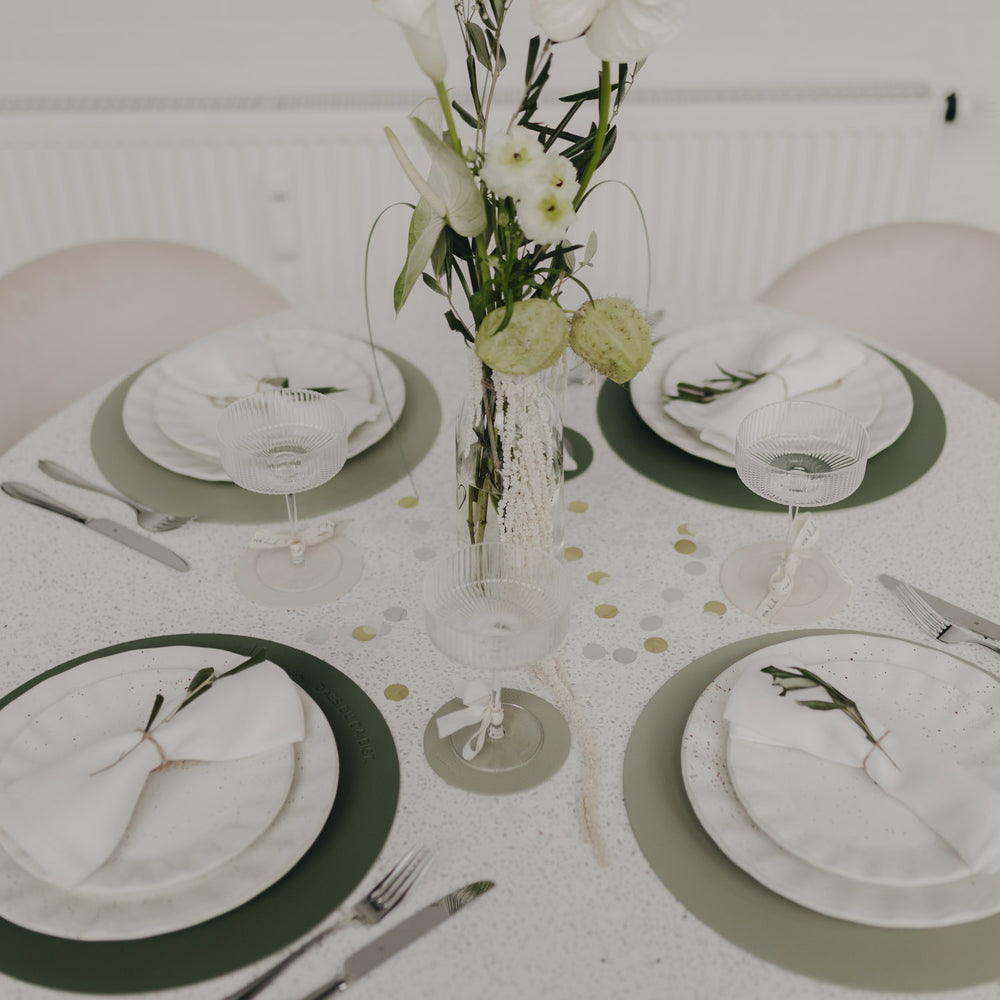 Festlich gedeckter Tisch mit grünen Platzsets und stilvoller Tischdekoration.