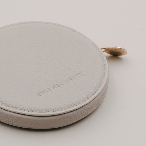 Detailaufnahme rundes Portemonnaie in Creme mit Eulenschnitt Prägung und goldenem Reißverschluss